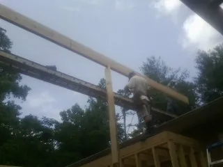 Carpenter setting a ridge beam over a new addition frame — Ice Dam Removal by Roofing Brothers in Rosman