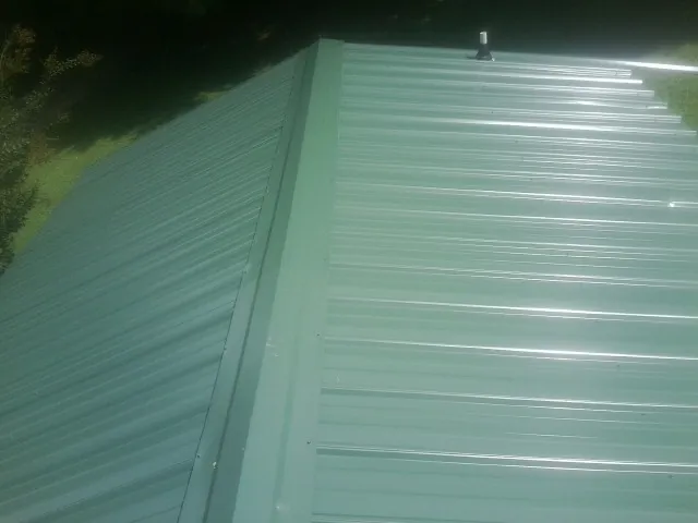 New green metal panels meeting at the ridge of a roof — Flat Roof Repair work by our crew in Rosman
