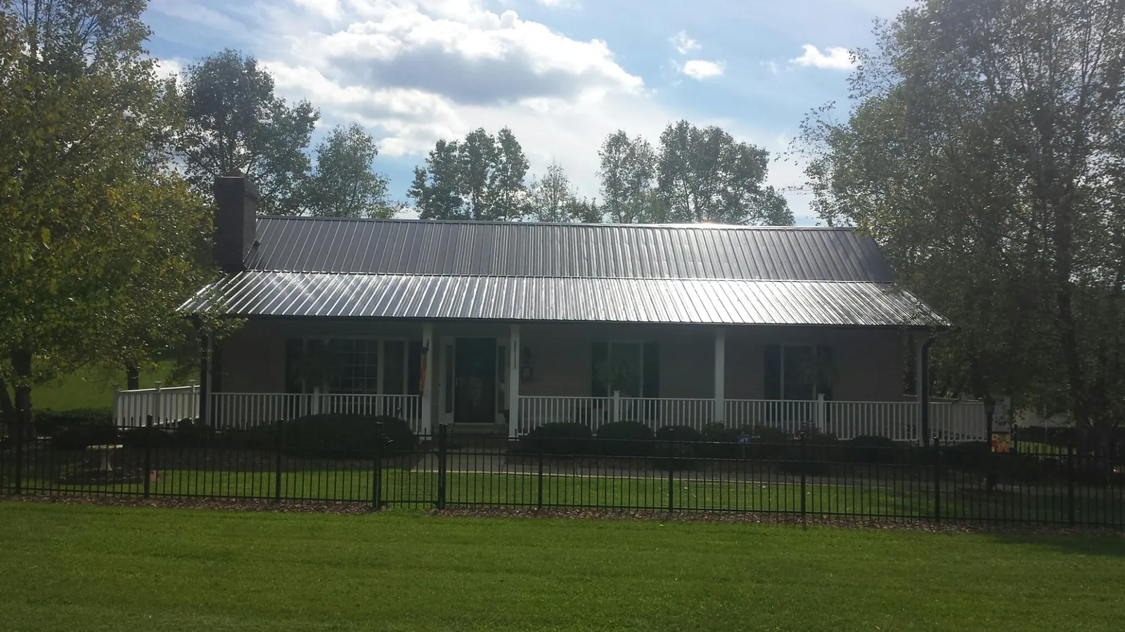Gray metal roof on a brick ranch with a full width front porch — Gutter Guard Installation work by our crew in Rosman